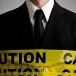 man in a black suit with caution tape wrapped around him.